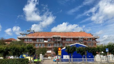 Äldre skolbyggnad under renovering, Träd till vänsterm byggbod till höger, trafikskylt i mitten