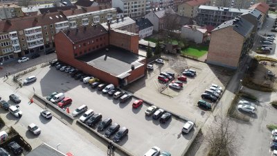 Drönarbild över kvarteret som till stor del består av en parkeringsplats. Omkringliggande gator och hus runt om.