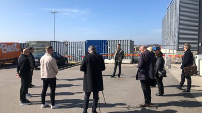 Personer som står i en ring runt David Mårtensson. Byggnad och containrar i bakgrunden.
