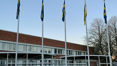 Fyra flaggor framför stadshuset. Vädret är fint och det blåser inte, så flaggorna hänger ner.