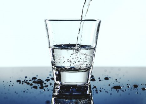 Halvfullt glas med vatten som fylls på. 