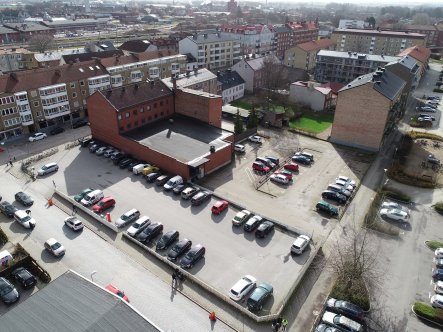 Drönarbild över kvarteret som till stor del består av en parkeringsplats. Omkringliggande gator och hus runt om.