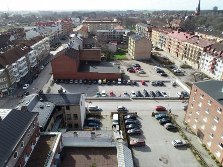 Drönarbild med parkeringsytor i förgrunden, tre gator i bild och många hus i bakgrunden