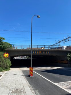 Lyktstople står mitt i cykelbana. Järnvägsbro i bakgrunden.