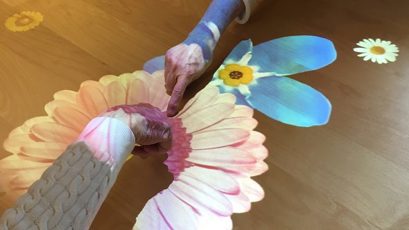 Händer som rör sig över en Tovertafel med blommor.